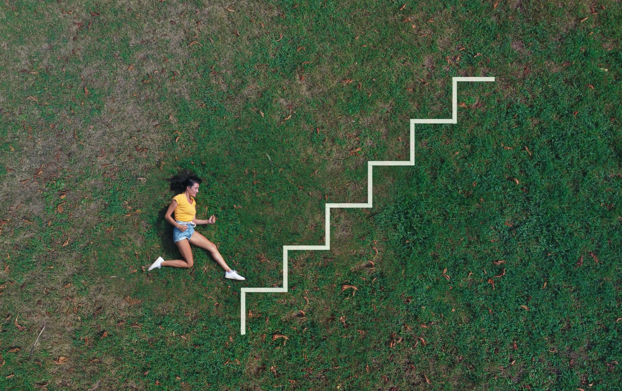 woman lying on a meadow pretends to run on a drawn ladder
