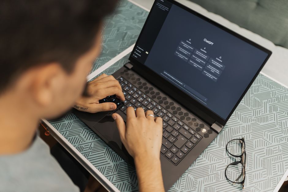 A business owner asking an AI assistant a question on a laptop