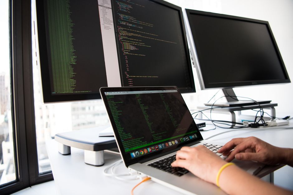 Developer auditing website scripts and plugins on two monitors