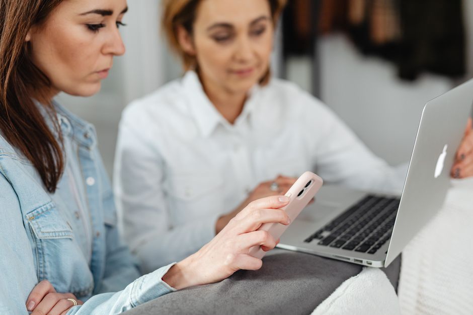 Customer researching on a phone before buying on a laptop