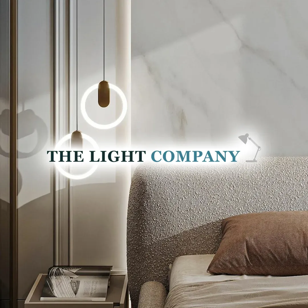 The Light Company logo over a modern bedroom lit by glass pendant lights